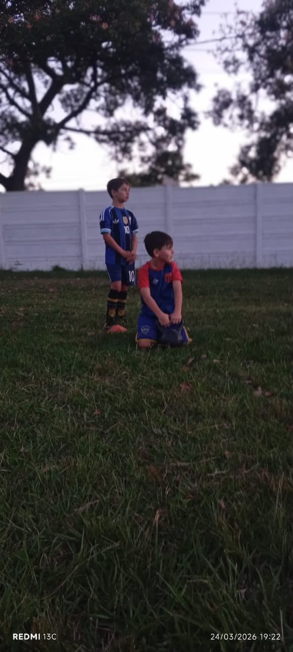 Chicos entrenando en la cancha al caer el sol